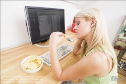 Viennaslide-72000371 Junge Frau isst Chips am Schreibtisch - Young woman eating chips at desk