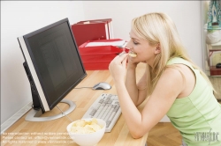 Viennaslide-72000374 Junge Frau isst Chips am Schreibtisch - Young woman eating chips at desk